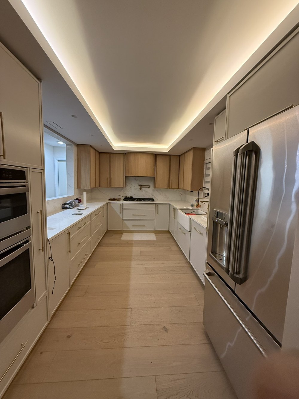 White and oak U-shaped kitchen with cove lighting, built by X-Trim Cabinets